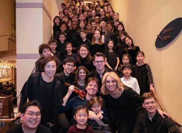 Amelia Gold, Elisabeth Morrow School chamber and superchamber conductor, poses with students on a staircase.