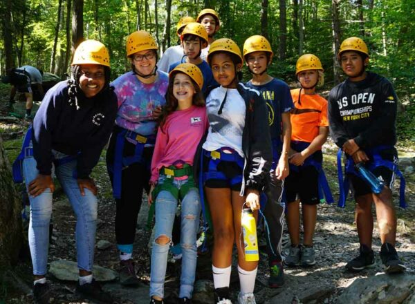 Fifth-, sixth-, and eighth-grade science teacher Dr. Stephanie Nebel and students pose in the woods while wearing hard hats.