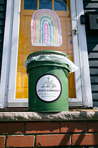 Green compost can on front step, a wooden front door in the background