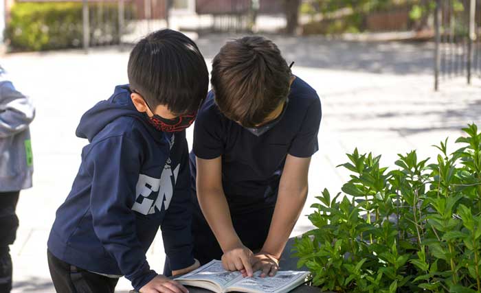 Two Elisabeth Morrow Students in Little School Studying a Book Outside