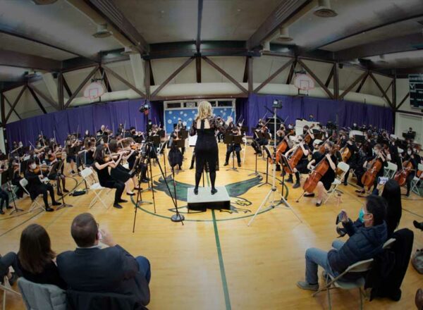 Winter Arts Festival image of Amelia gold conducting Elisabeth Morrow School orchestra in the gym with parents watching