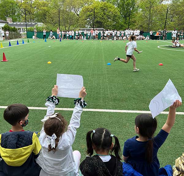 Younger students cheering on the older students at Field Day