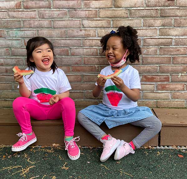 Two friends enjoying watermelon during the Watermelon Picnic