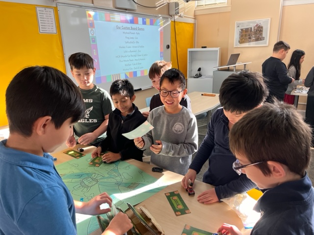 Students showing off the board game they created.