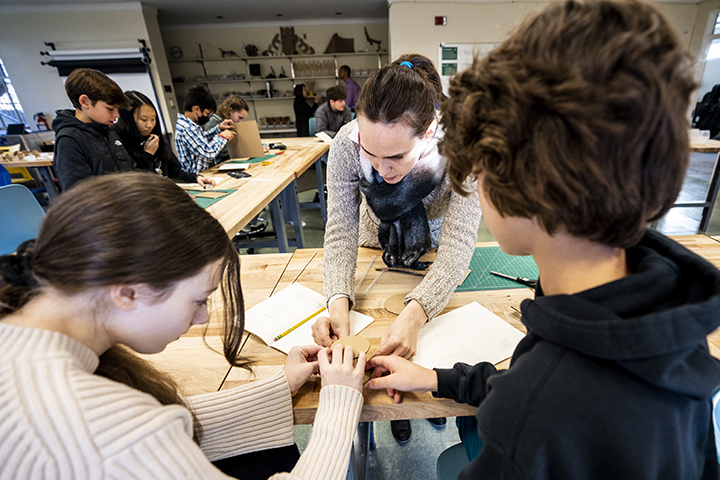 Teacher assisting students as they work on their NuVu projects.