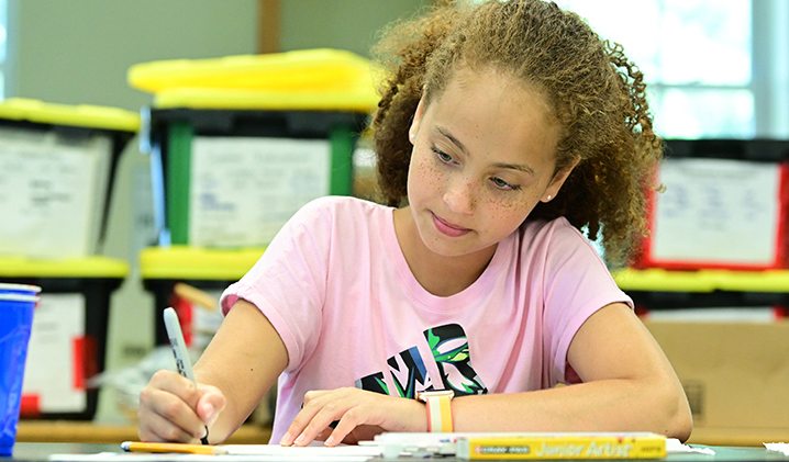 Student writing at a desk.