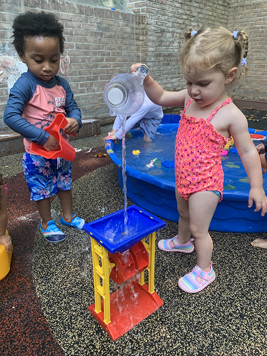 Two young students playing during water play.