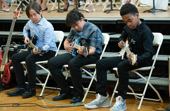 A trio of students playing guitar.