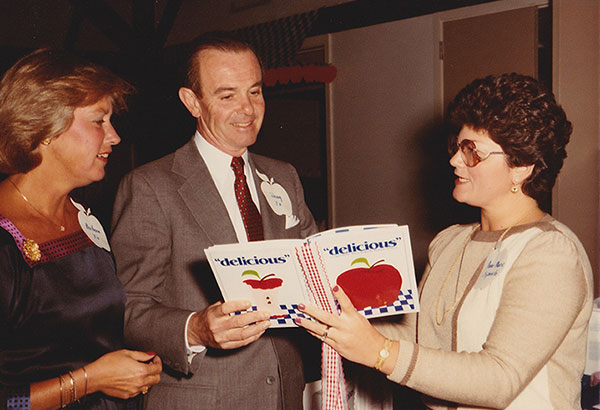 Community members looking at the new delicious cookbook, circa 1982-84.