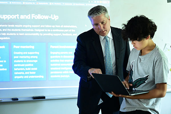 Head of School Marek Beck showing a student something during his AI class