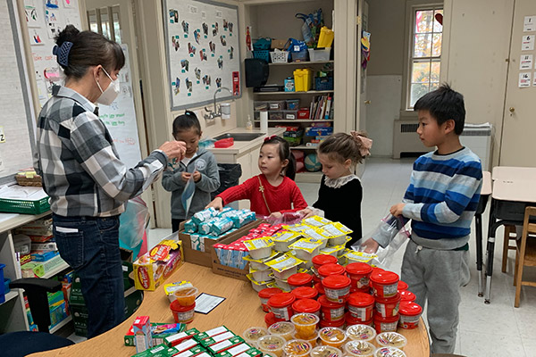 CFA representative Lori Oliff helping Little School students pack snack packs.