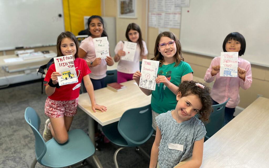 Children holding up books they created themselves