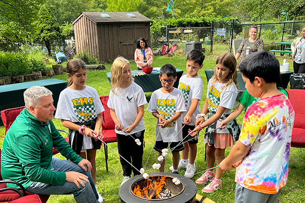 Students outside roasting marshmallows with Head of School Marek Beck during Adventure Week.