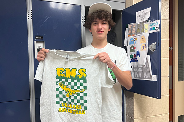 EMS alum Misha Theberge holding up this year's Adventure Week T-shirts that he designed.
