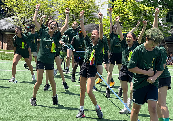 The green team cheers during Field Day after a tug-of-war win.