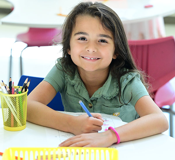 Child smiling while sitting at desk.
