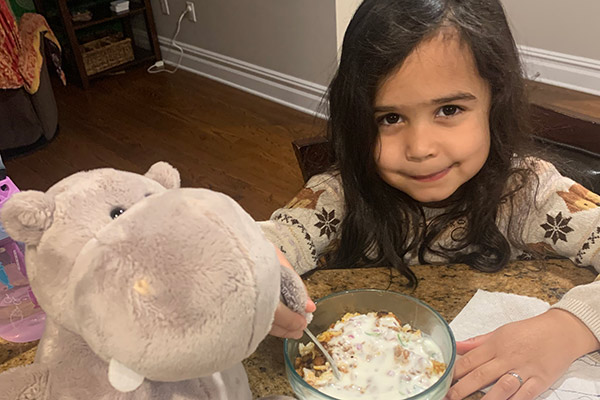 A 3s/4s student enjoying dinner with the class stuffed animal.