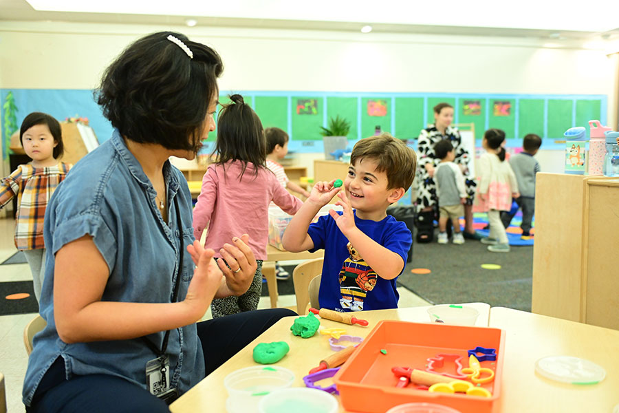 Our youngest learners smiling with their teacher while participating in an activity.