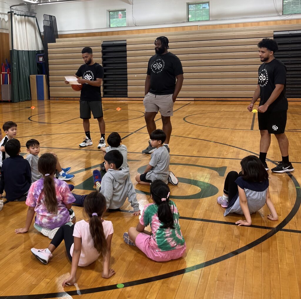 The coaches of 99% Sports at EMS speaking with young students of the program.