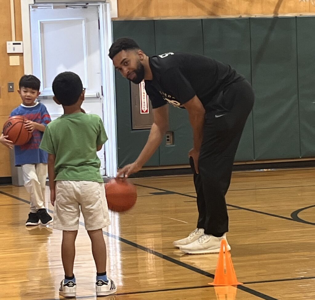 A'Jahn Huggins of 99% Sports helping a young student with their basketball skills.