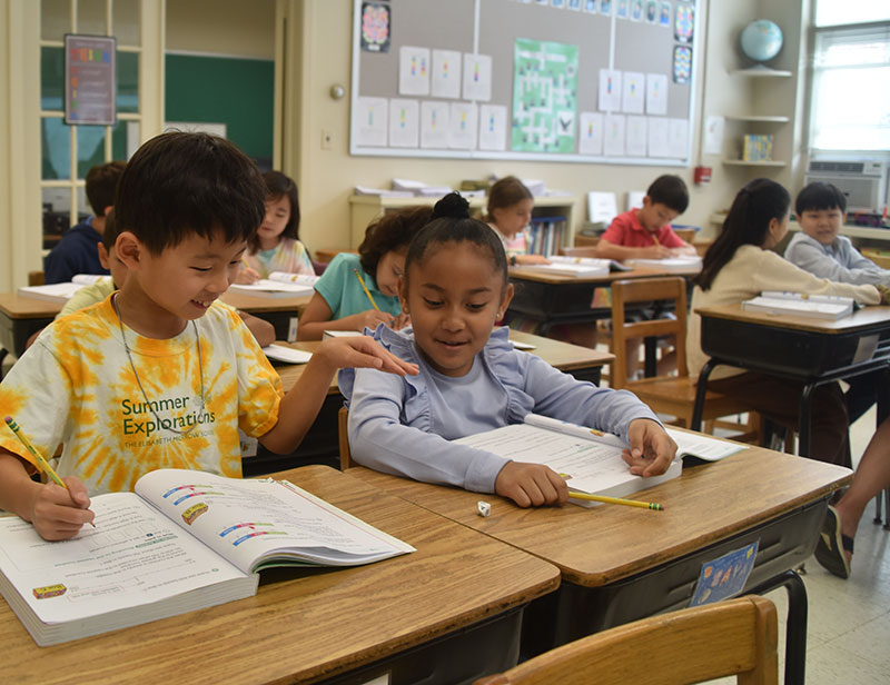 Two Little School students in third grade working together through a math problem.